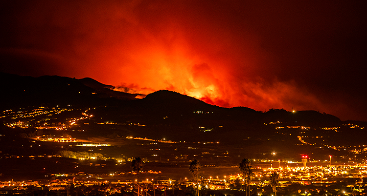 Bilden är tagen på kvällen. Det är mörkt. Elden syns som röda flammor bakom staden.