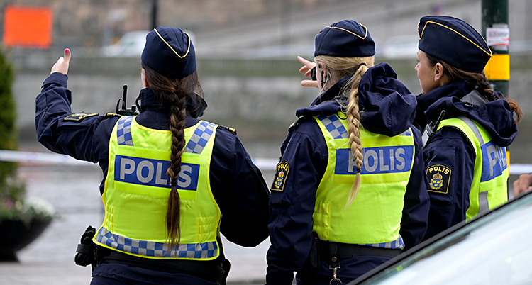Tre kvinnliga poliser står utomhus och pratar.