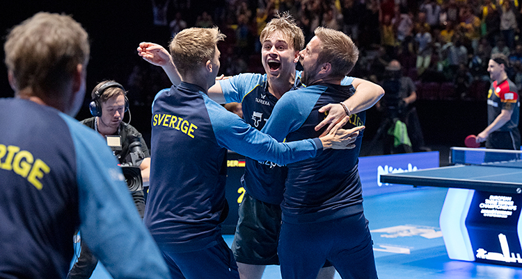 Några killar jublar och kramas i en hall för bordtennis.