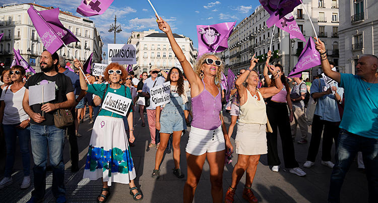 Människor går på gatan och protesterar med lila flaggor.