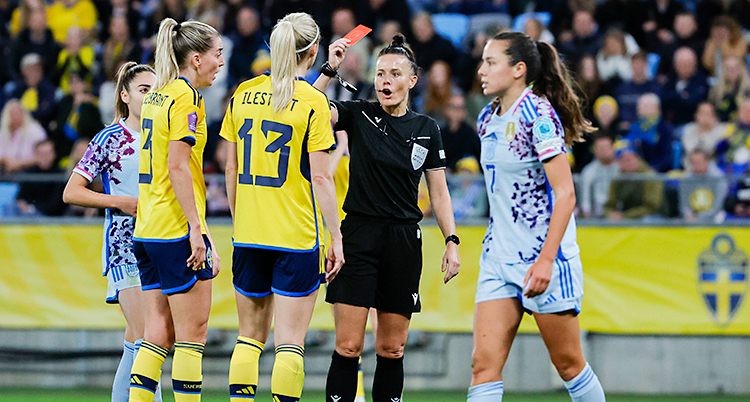 Från en match i fotboll. Några spelare står runt domaren. Domaren lyfter det röda kortet.