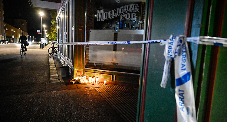 Det är mörkt ute. Poliserna har spärrat av utanför en krog. Det brinner flera ljus.