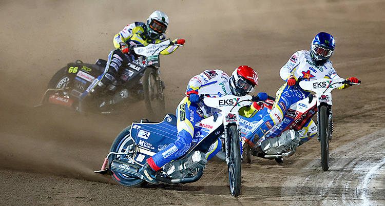 Från en tävling i speedway. Tre personer kör på varsin motorcykel.