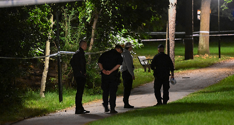 Flera poliser står på en väg. Det är mörkt. Platsen är avspärrad med tejp.