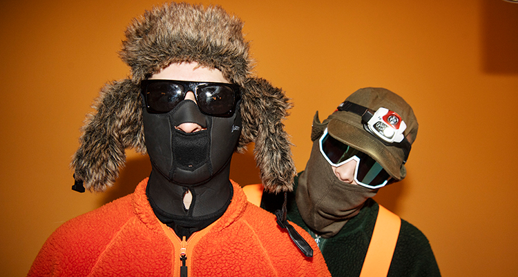 De två i Hooja stor bredvid varandra med masker för ansiktet och mössor.