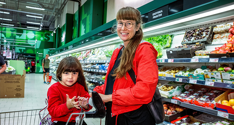 De har båda röda jackor på sig. Barnet åker i en kundvagn.