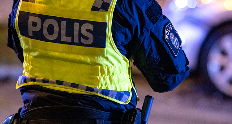 En rygg på en polis som har gul väst på sig.