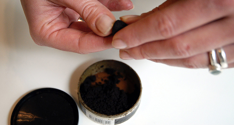 En hand rullar en prilla med snus.