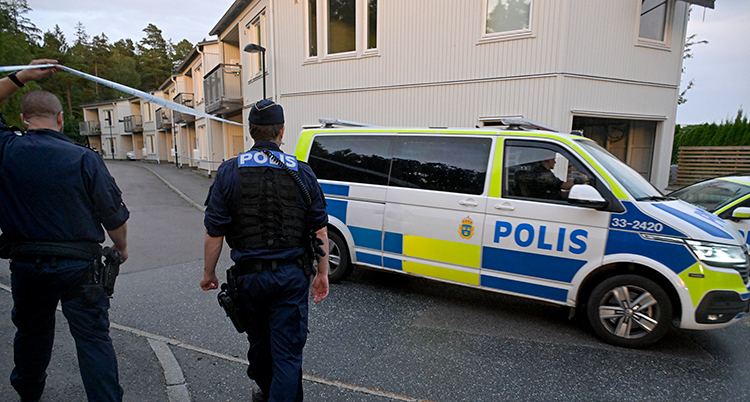 En polisbuss står bredvid ett hus.