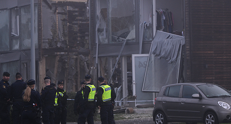 Poliser framför förstörda hus.