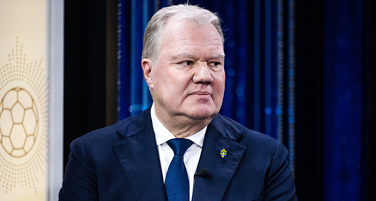 En närbild på honom. Han ser allvarlig ut och tittar åt sidan.
