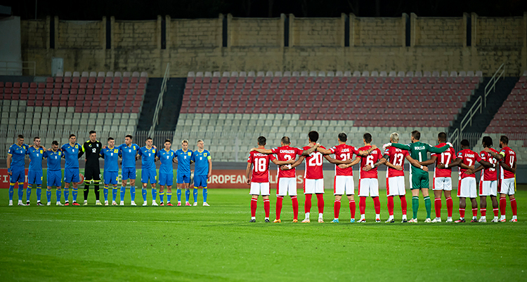 Två lag står mitt emot varandra på en fotbollsplan.