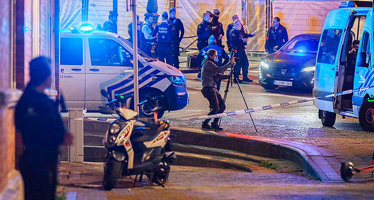 Poliser, polisbilar och avspärrningar på en gata.