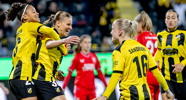 Flera spelare i gula tröjor kramar om varandra på fotbollsplanen.