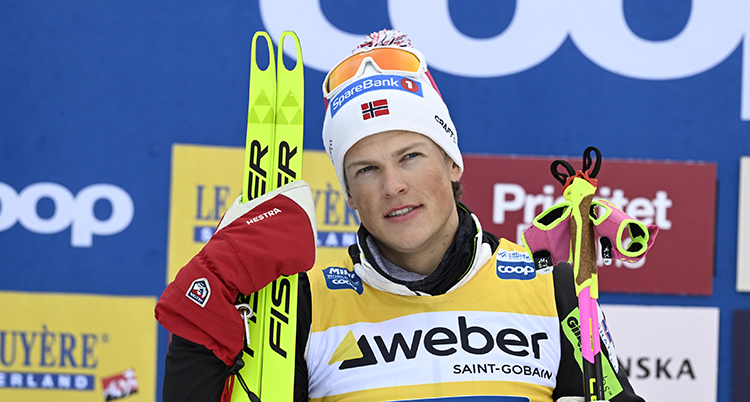 Kläbo håller ett par skidor och stavar.
