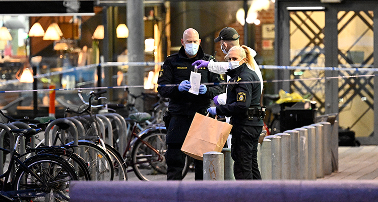 Poliser med munskydd lägger saker i en påse.