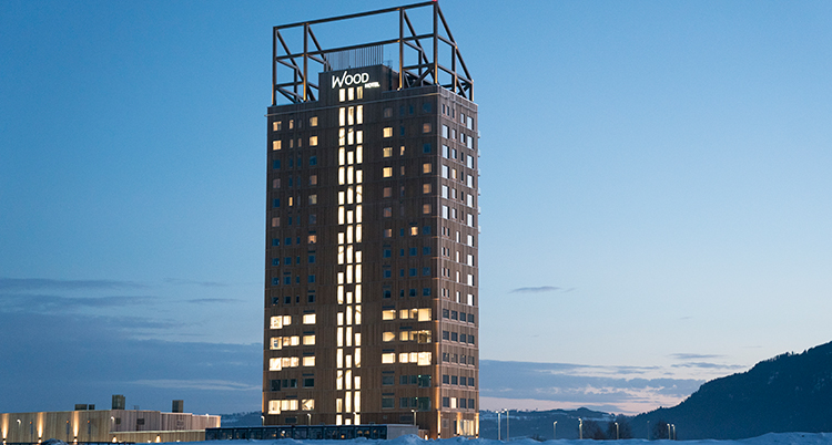 Ett högt hus i trä. Det lyser i fönstren. Himlen är blå.