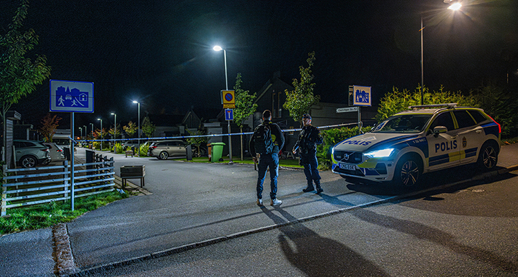 En avspärrad gata. Två poliser står på gatan.