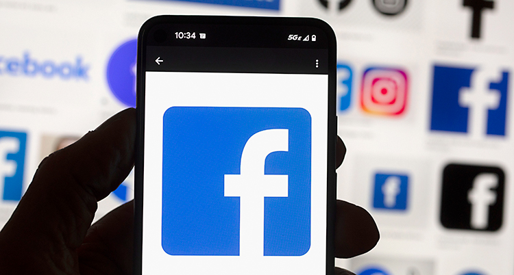 En hand som håller upp en mobiltelefon. Där syns symbolen för Facebook.