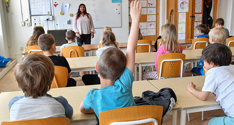 Elever i ett klassrum med en lärare längst fram.