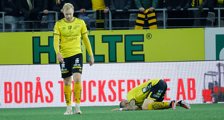En spelare går med hängande huvud, en annan ligger på knä med ansiktet mot gräset.