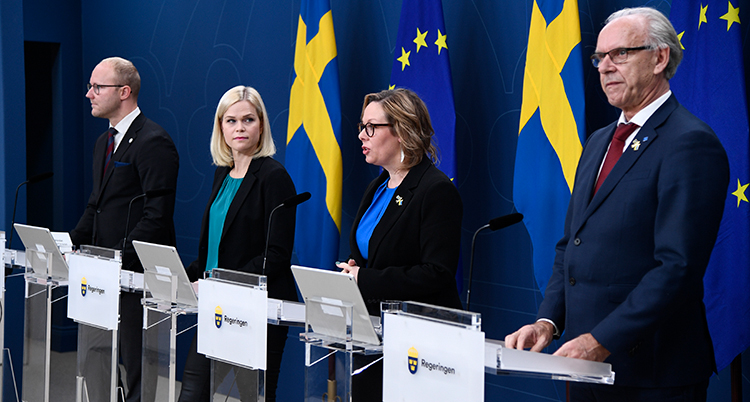 Fyra personer på rad bakom varsitt litet bord.