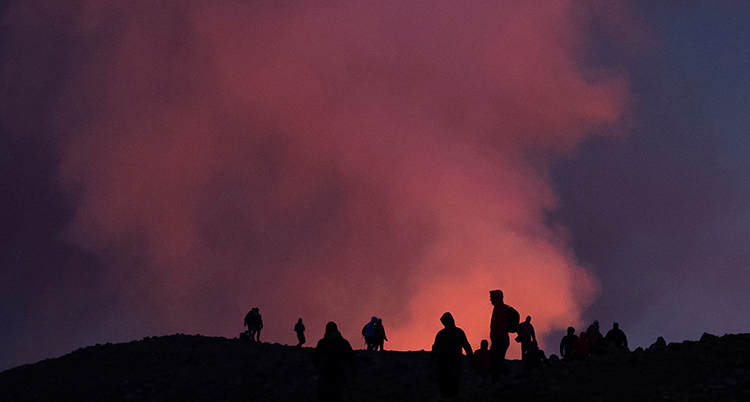 Himlen är röd och människor står på ett berg.