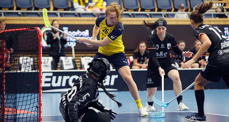 Svensk spelare slår med klubban bland flera svartklädda spelare.