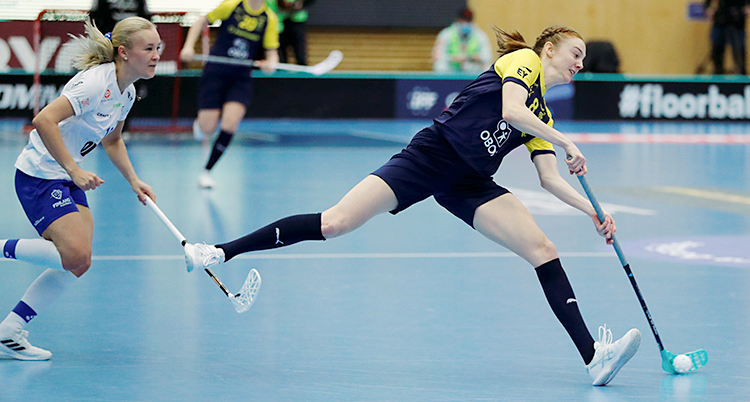 Från en match i innebandy. En svensk spelare har bollen. Hon jagas av en finländsk spelare.