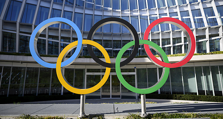 Stora olympiska ringar som står utanför ett stort hus.
