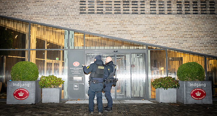 Det är mörkt. Två poliser står utanför ett hus.