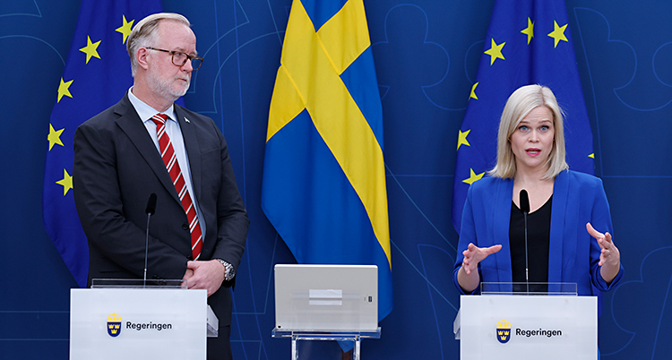 De står bredvid varandra och pratar i mikrofoner på en träff med journalister.