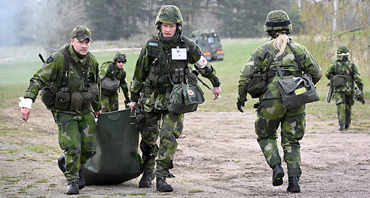 Några soldater i gröna kläder som är utomhus.