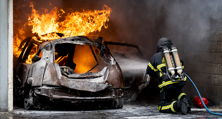 Brandmannen sprutar med en slang mot bilen.