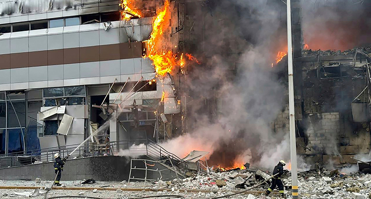 Brandmän försöker släcka en brand i ett skadat hus.