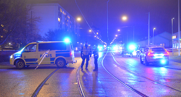 Två poliser och en polisbuss står på en gata.