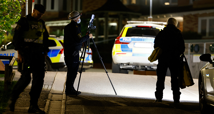 Flera polisbilar och poliser med utrustning i mörker.