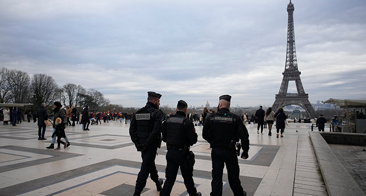 Tre poliser framför eiffeltornet i Paris.