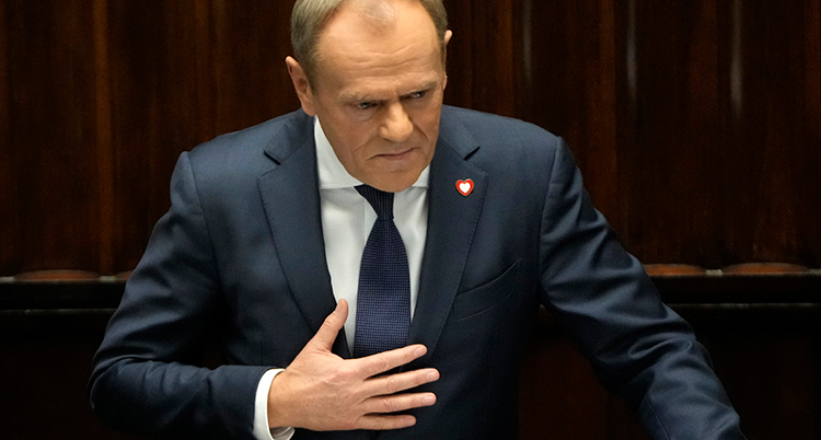 Donald Tusk i kostym har en hand på bröstet.