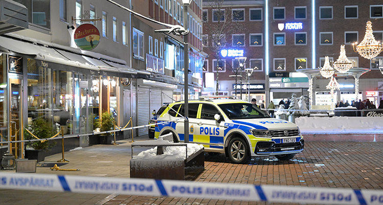 Polisbil och avspärrning på ett torg.