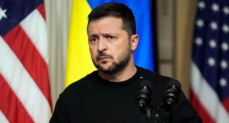Han står framför USAs och Ukrainas flaggor. Han ser bekymrad ut.