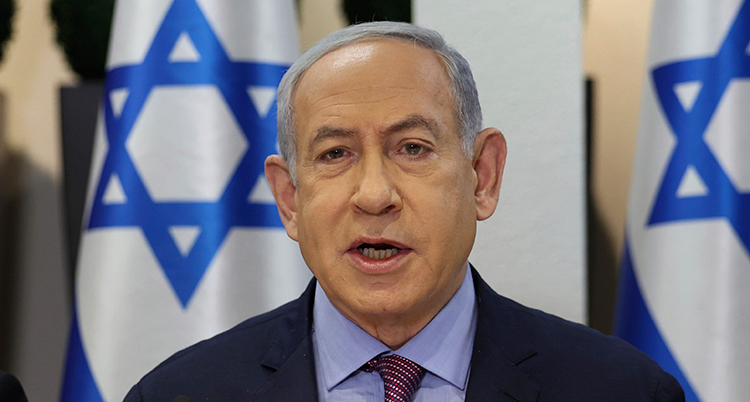 Han pratar in i kameran. Bakom finns israeliska flaggor.