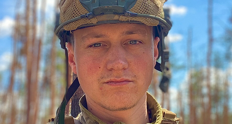 En nära bild. Han har en hjälm på huvudet och militärkläder.