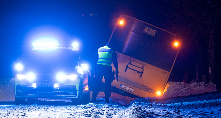 Polisbil vid buss som kört i diket.
