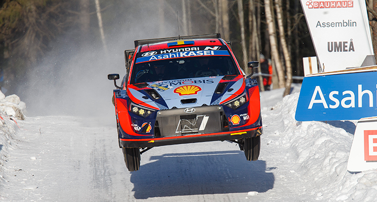 En rallybil på en snöig smal väg.
