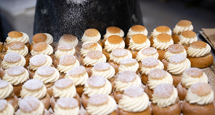Många nybakade semlor på ett bord.