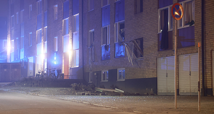 Utsidan av ett hus med lägenheter. Flera fönster är trasiga.