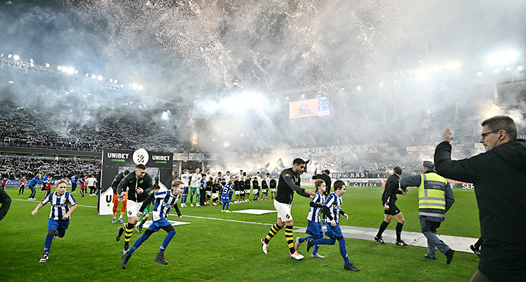 Folk är på en fotbollsplan. De springer för att komma undan raketerna som personer i publiken skjuter in på planen.