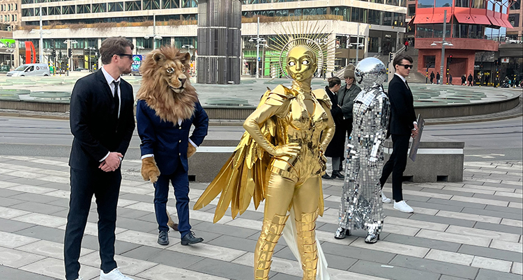 Personer i kostymer och dräkter syns i en stad.
