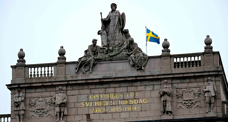 Figurer i sten och text i guld vid taket på riksdagens hus.